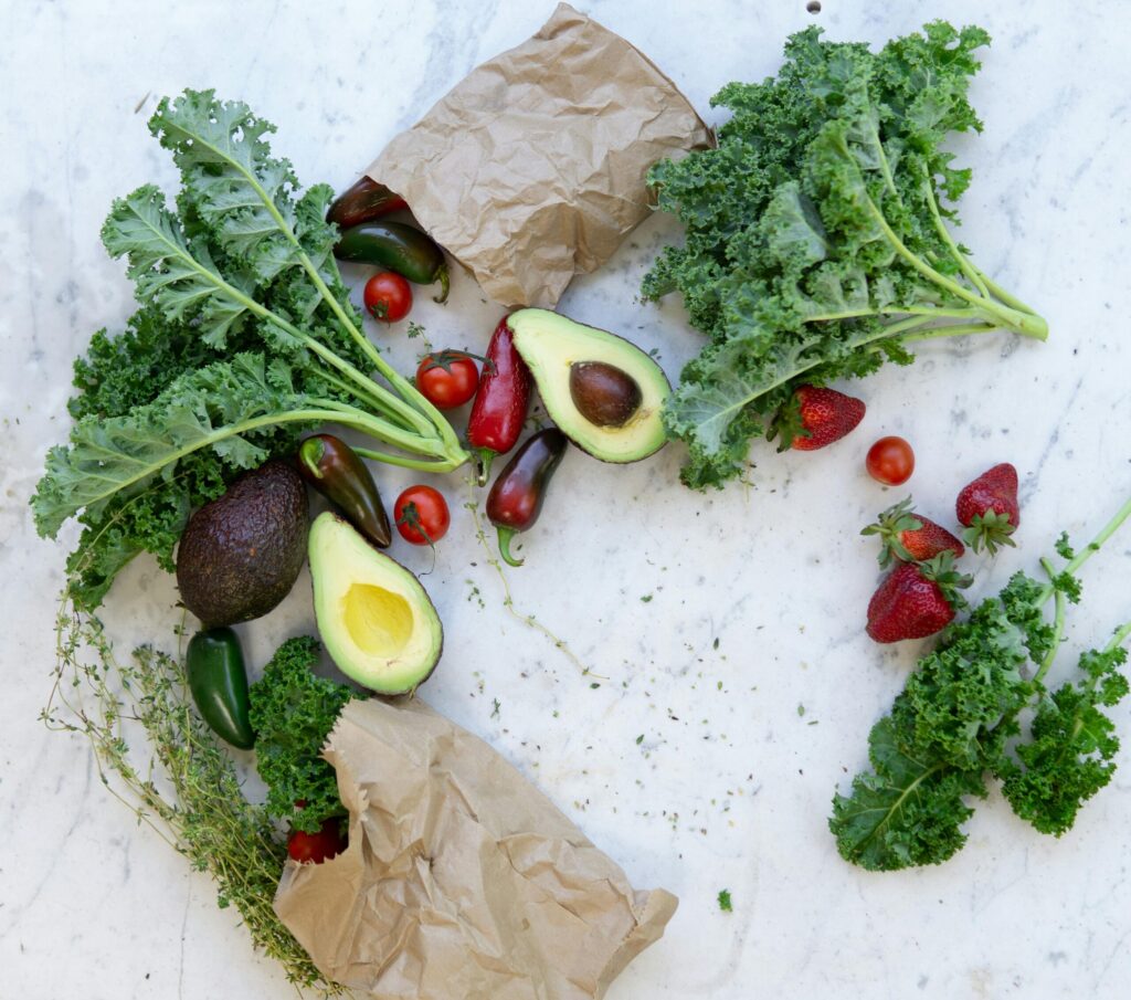 pexels-photo-1660027-1660027 Top view of fresh avocados, kale, tomatoes, and peppers arranged on a marble surface.