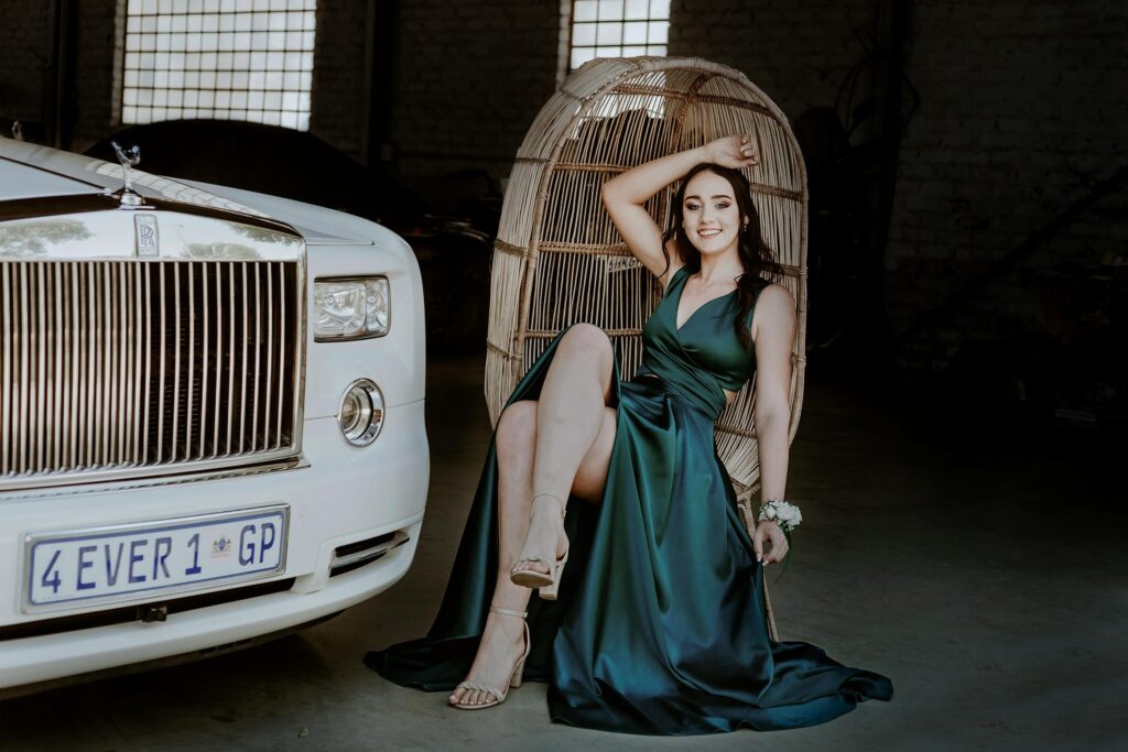 A sophisticated woman in a green dress poses with elegance beside a luxury car in Pretoria.